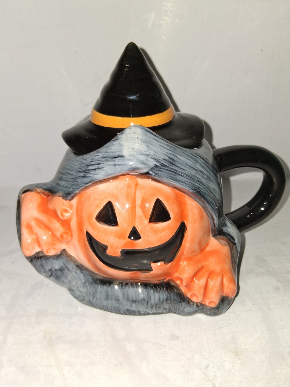 Halloween Earthenware Mug, featuring a jack-o'-lantern pumpkin peeking out .